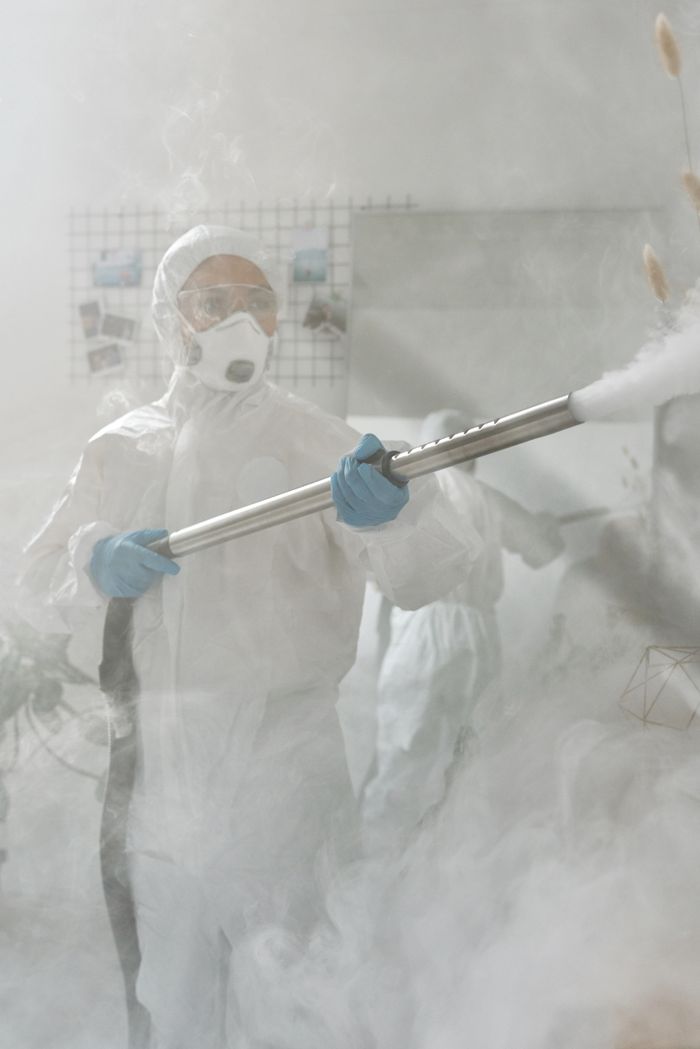 creative-03 A person in complete protective gear fumigating a room to help ensure sterilization against viruses.